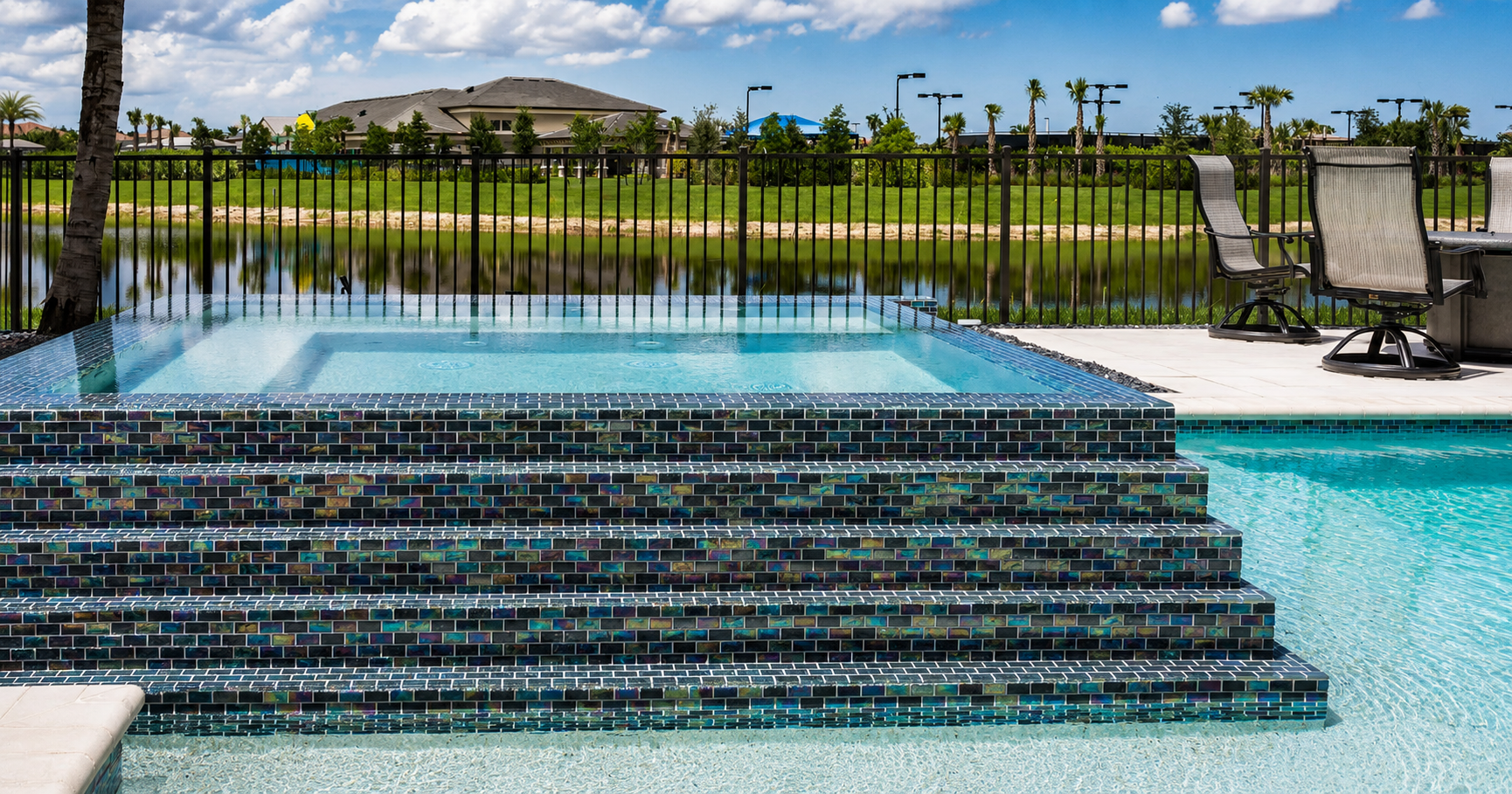 Luxury backyard pool and raised spa featuring Black Steel iridescent 1x2 glass mosaic tile with a modern outdoor living space.