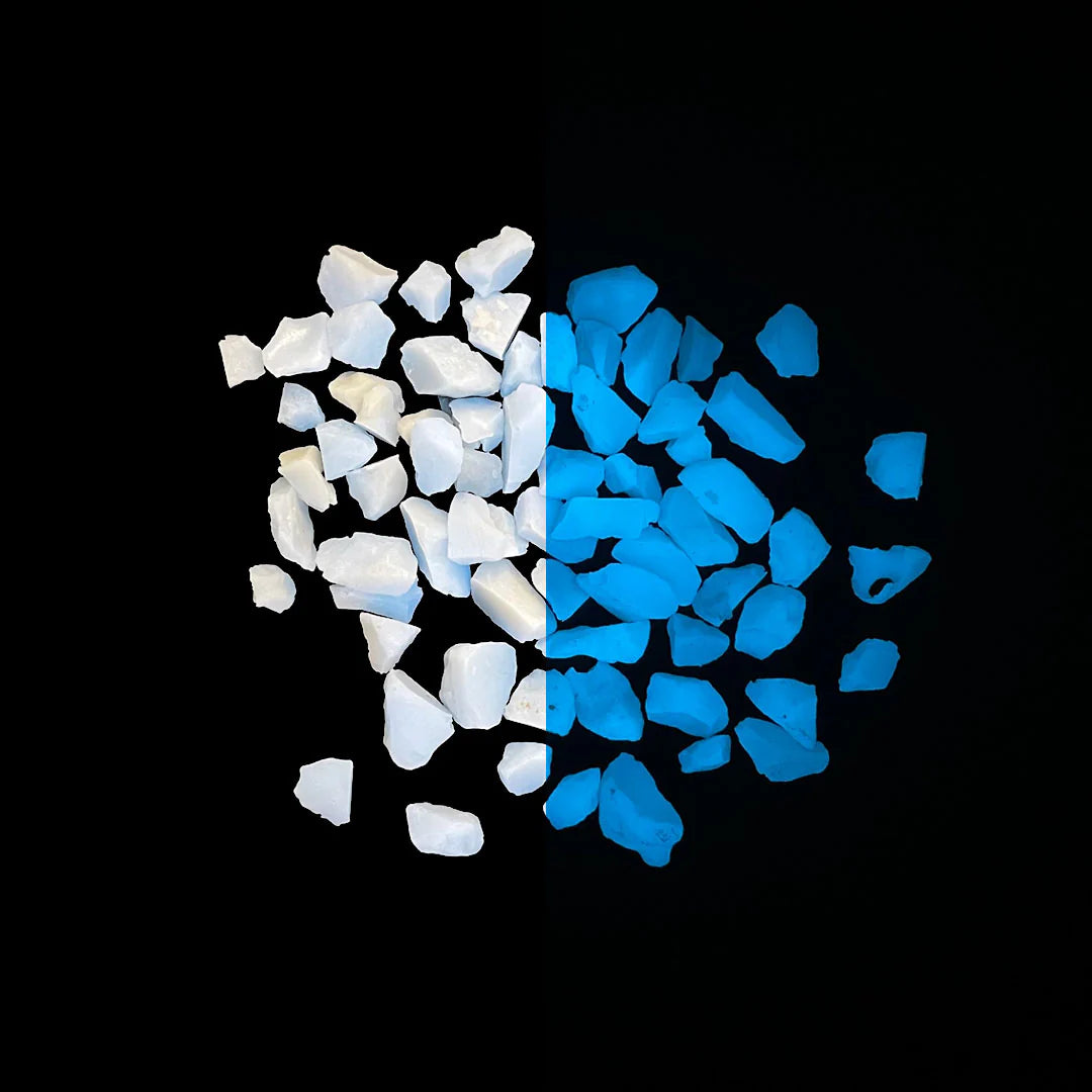 Close-up of glow-in-the-dark filter media granules showing a side-by-side comparison of natural white appearance and blue luminescent glow on a black background